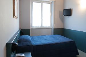 a small room with a blue bed and a window at Hotel Tirreno in Genoa