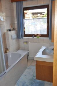 een badkamer met een bad, een toilet en een wastafel bij Ferienwohnung Pezzei in Schlitters