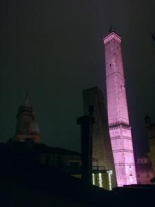 un'alta torre illuminata di rosa di notte di YAWHome B&B a Bologna