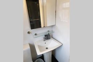 uma casa de banho com um lavatório branco e um espelho. em South Shield's Hidden Gem Garnet 3 Bedroom Apartment sleeps 6 Guests em South Shields