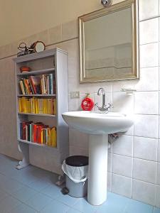 un bagno con lavandino e una libreria con libri di Casa Ariodante a Perugia