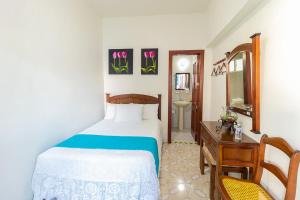 a bedroom with a bed and a table and a mirror at Hotel Casa Blanca by Rotamundos in Tlacotalpan