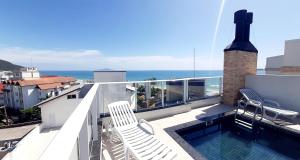 Un balcón con dos sillas y una piscina. en Apartamento Gaivotas - 20 metros do mar, lazer e home office, en Florianópolis