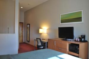 a hotel room with a bed and a flat screen tv at The Soluna Hotel in El Paso
