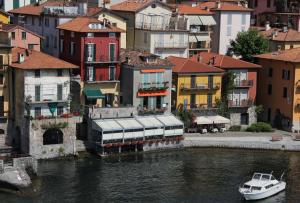 ein Boot in einem Wasserkörper mit Gebäuden in der Unterkunft Albergo Milano in Varenna