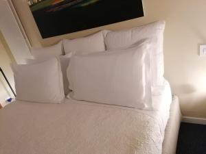 Una cama blanca con almohadas blancas encima. en BC MAISON bed&cafe Milano en Milán