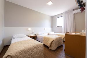 a hotel room with two beds and a desk at Hotel Lunes in São José +60 photos