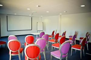 een klaslokaal met rode en paarse stoelen en een whiteboard bij Adonis La Baule in La Baule