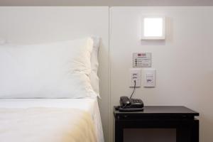 ein Schlafzimmer mit einem Bett und einem Telefon auf einem Tisch in der Unterkunft Hotel Lunes in São José