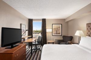 レジャイナにあるRoyal Hotel Regina, Trademark Collection by Wyndhamのベッド1台、薄型テレビが備わるホテルルームです。
