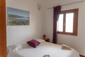 ein Schlafzimmer mit einem weißen Bett und einem Fenster in der Unterkunft Case Fiorite in Riola Sardo