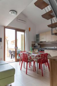 a kitchen with a table and red chairs in a room at Case Fiorite in Riola Sardo