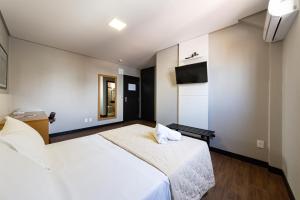 ein Schlafzimmer mit einem großen weißen Bett und einem Spiegel in der Unterkunft Hotel Lunes in São José