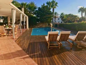 a deck with chairs and a swimming pool at Villa Victoria in Sa Caleta