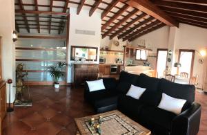 sala de estar con sofá negro y cocina en Villa Victoria, en Sa Caleta