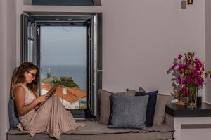 a woman sitting on a couch reading a book at CAMARA SUITES in Andros