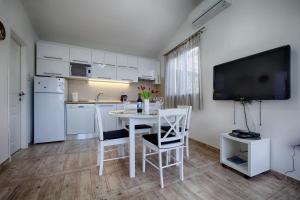 TV y cocina con mesa y sillas blancas. en Villa Franceska, en Vis