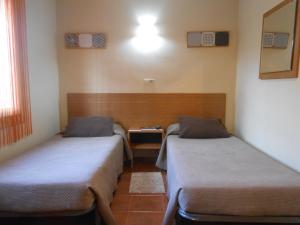 Habitación con 2 camas y mesa. en Hostal El Callejón, en Tarragona