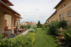 einen Garten mit Pflanzen und Blumen neben Gebäuden in der Unterkunft Élet es Energia Egészségjavító Szalon in Nagykőrös