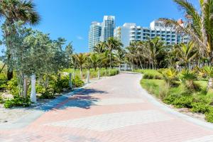 邁阿密海灘的住宿－Welworth condo units Miami Beach，公园里种有棕榈树和建筑的走道