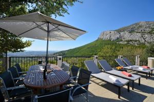 a table and chairs with an umbrella on a patio at Villa Anteana with view and pool of 60m2 in Solin
