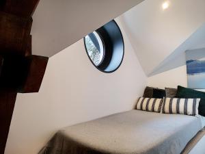 Cette chambre comprend un lit et une fenêtre ronde. dans l'établissement La Viralamande by Cocoonr, à Crépieux-la-Pape