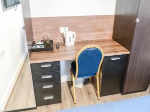 a desk with a blue chair in a room at La Tavola Calda Hotel in Nuneaton