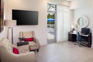 a living room with a tv and a chair and a desk at Star Suites - An Extended Stay Hotel in Vero Beach