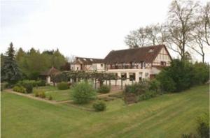 una casa grande en un campo con un patio en Logis Hôtel Restaurant Le Coq Hardi, en Pouilly-sur-Loire