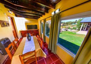 ein Esszimmer mit einem langen Tisch und einem großen Fenster in der Unterkunft Cabañas Brisas del Cerro in Los Reartes