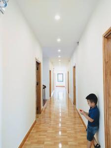 Un ragazzo è in piedi in un corridoio di AKU HOUSE Villa Ao vua a Ba Vì