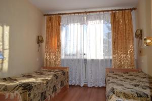 a bedroom with two beds and a window with curtains at Hotel Planeta in Pechory