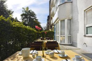 a table with plates and cups and a flower on a patio at Hotel AMENITY in Munich