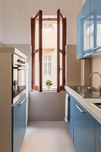 a kitchen with blue cabinets and a window at A World Aparts - 55 Palermo in Rome
