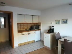 małą kuchnię z białymi szafkami i kuchenką mikrofalową w obiekcie Apartment Waldhaus Opitz w mieście Zell am See