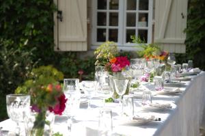 una mesa larga con vasos y flores. en Le Mas d'en Haut, en Lussat
