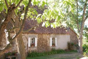 a stone house with two windows and a tree at Le Mas d'en Haut in Lussat