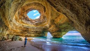 a person standing on a beach in front of a cave at Casa Bela Moura, Boutique Hotel & Wine in Porches