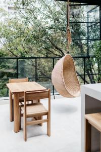 a rattan swing hangs in a room with a table and a chair at Casa Pancha in Mexico City