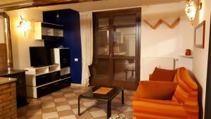 a living room with an orange chair and a television at Appartamento Presanella in Passo del Tonale