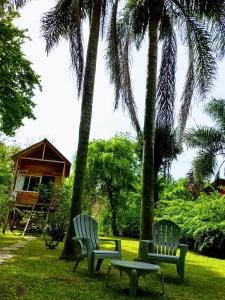 dos sillas y una mesa en un patio con palmeras en Cabañas Le Parc en Delta de Tigre en Tigre