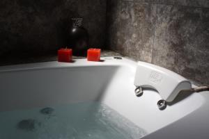 a white bath tub with two candles on top of it at Hotel Risco Plateado Room & Suite in Malargüe