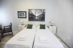 biała sypialnia z 2 łóżkami i krzesłem w obiekcie Apartamento Mar de Korus w Maladze
