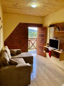 a living room with a couch and a television at Chalé Bela Vista - Chalés Belo Monte in Pacoti