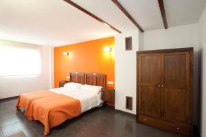 a bedroom with a bed and an orange wall at Casa Rural Casole in Castalla