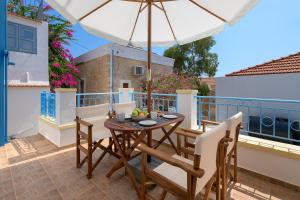 a table and chairs on a balcony with an umbrella at Anastasia house in Halki