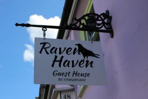 um sinal para uma casa de hóspedes com um pássaro nela em Raven Haven Glastonbury em Glastonbury