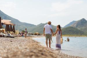 a man and a woman walking on the beach at Hotel Savojo in Petrovac na Moru