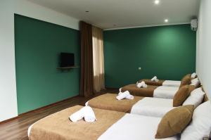 Habitación con 4 camas y pared verde. en Taba Hall Boutique Hotel, en Akhaltsikhe
