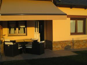 une maison avec une table et des chaises sur une terrasse dans l'établissement APARTAMENTOS FONTE VILLAR, à Navia